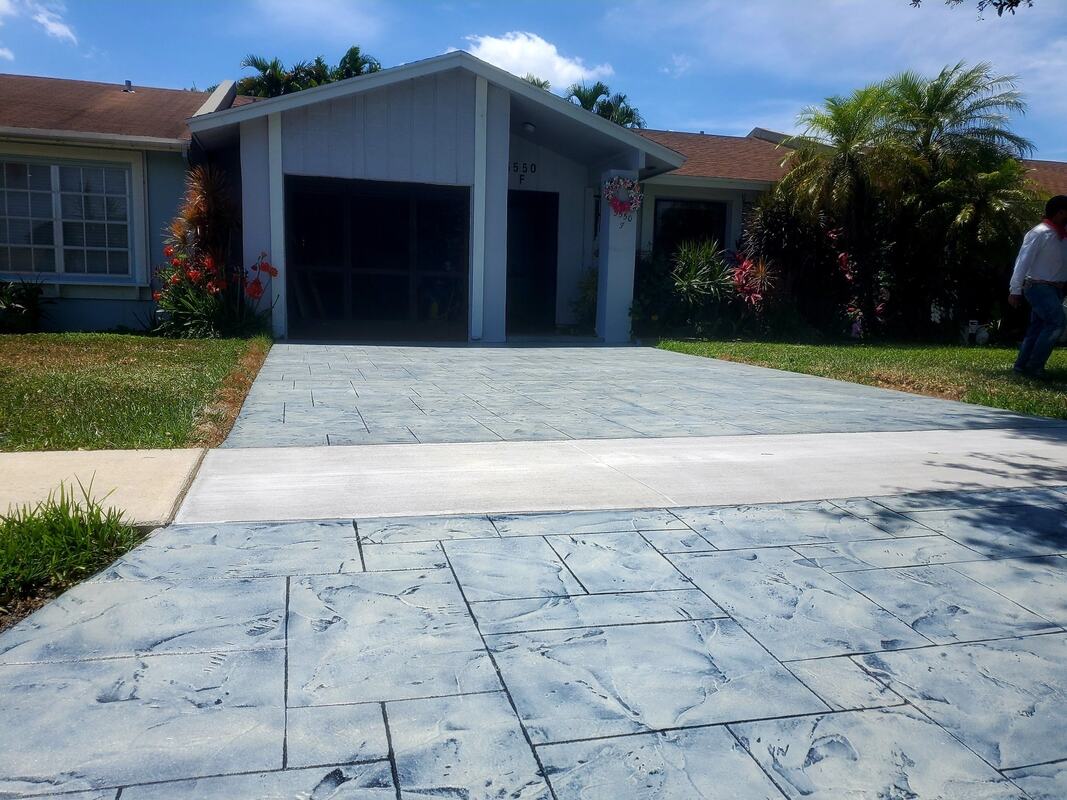 curved stamped concrete driveway in dark gray bordered by light gray stone. 