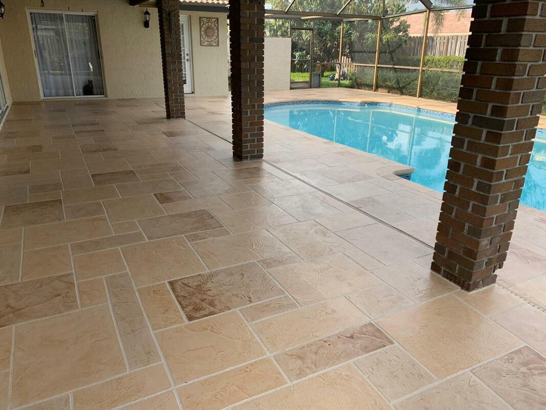 Picture of the back patio of a house finished with a stamped concrete patio in a decorative pattern overlooking a nice pool