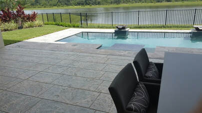 Picture of a house with a beautiful stamped concrete pool deck overlooking the pool