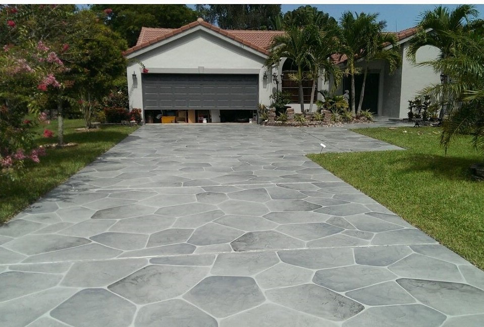 Picture of a stamped concrete driveway in gray stone pattern highlighted by the reflection of the sun